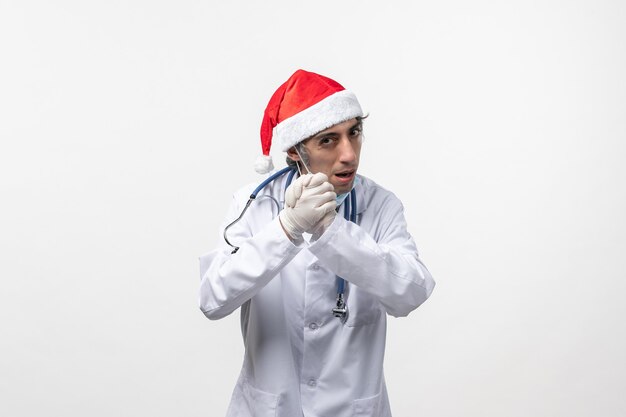 Vista frontal médico masculino con guantes en la pared blanca covid de vacaciones de virus- emoción