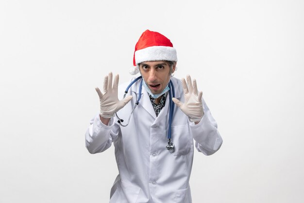 Vista frontal médico masculino con guantes en la pared blanca covid de vacaciones de virus- emoción