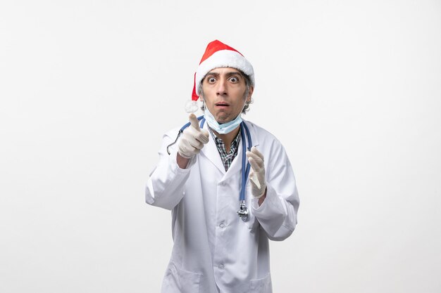 Vista frontal médico masculino con guantes en la pared blanca emoción covid de vacaciones de virus