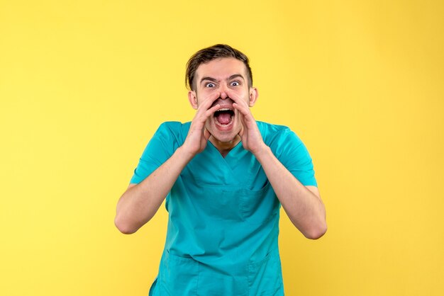 Vista frontal del médico masculino llamando en voz alta a la pared amarilla