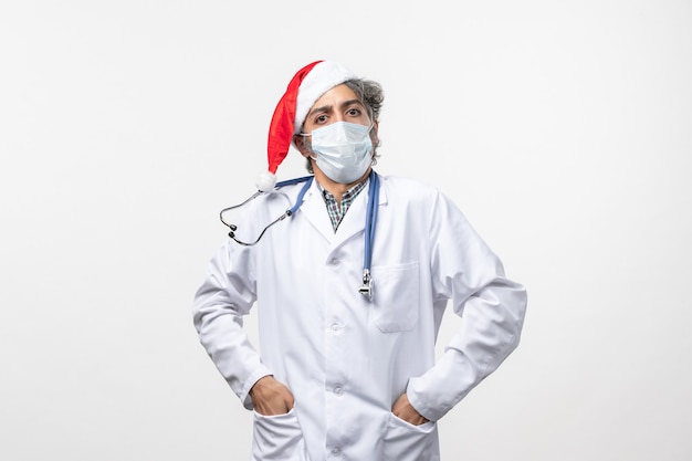 Vista frontal médico masculino en máscara estéril en la pared blanca pandemia de año nuevo del virus covid