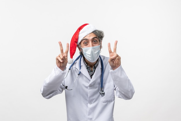 Vista frontal médico masculino con máscara estéril en la pared blanca pandemia de virus covid de año nuevo