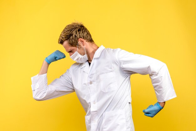 Vista frontal médico masculino en máscara flexionando sobre fondo amarillo virus salud covid-pandemia