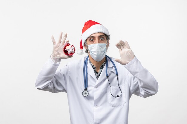 Vista frontal médico masculino en máscara con juguete en pared blanca salud virus covid año nuevo