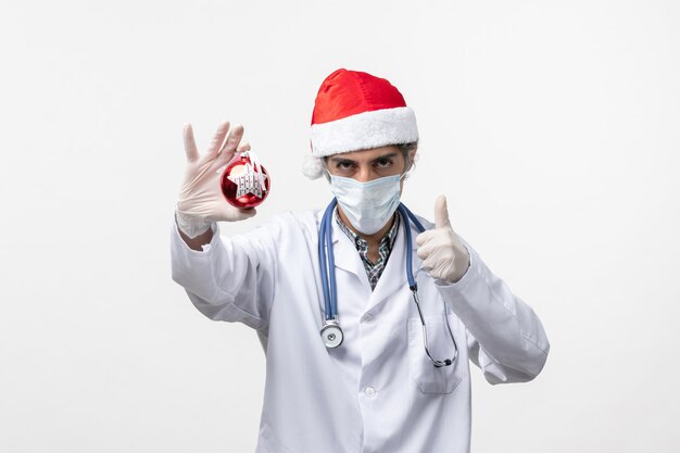 Vista frontal médico masculino en máscara con juguete en la pared blanca virus covid health año nuevo