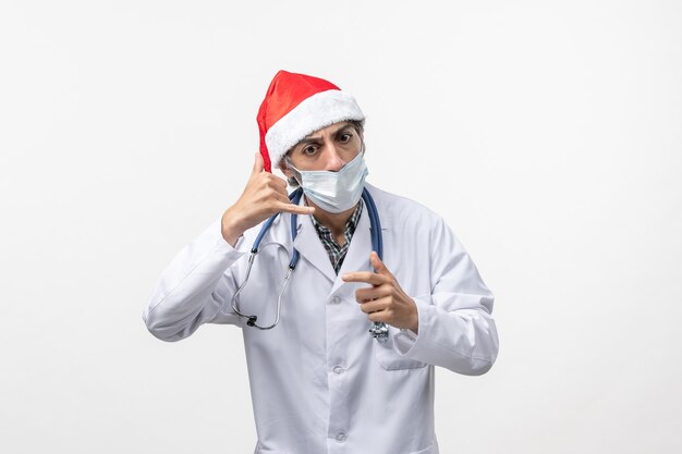 Vista frontal médico masculino con máscara en una pared blanca virus pandémico de vacaciones covid