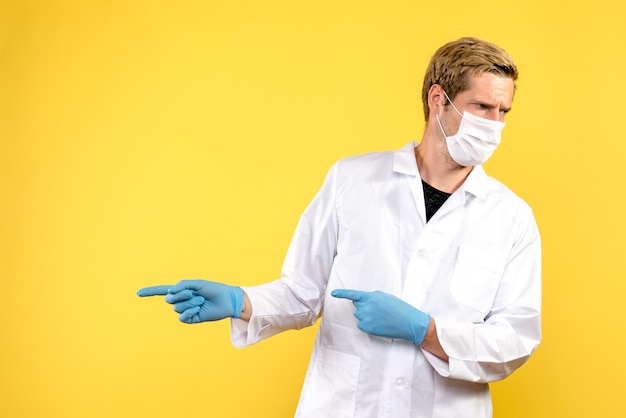 Vista frontal médico masculino en máscara sobre el fondo amarillo salud pandemia covid virus