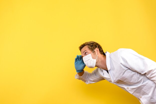 Vista frontal médico masculino en máscara sobre fondo amarillo salud pandémica covid