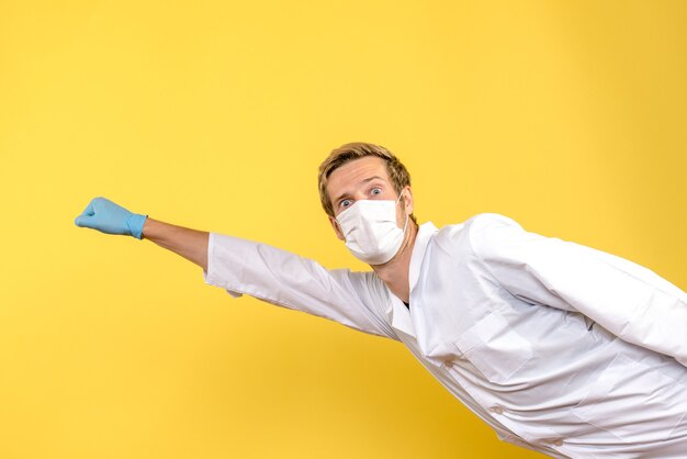 Foto gratuita vista frontal médico masculino en pose de superman sobre fondo amarillo médico de salud pandémica covid