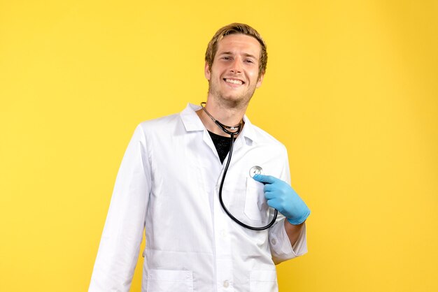 Vista frontal médico masculino smilign sobre fondo amarillo salud virus médico emoción