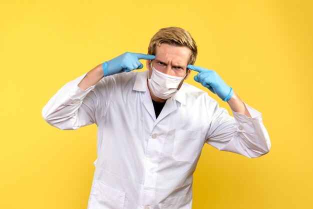 Vista frontal médico masculino sobre fondo amarillo médico pandémico covid- salud