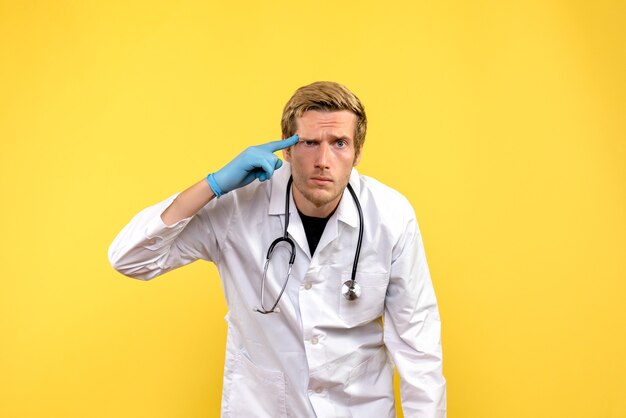 Vista frontal médico masculino sobre fondo amarillo médico de salud virus humano