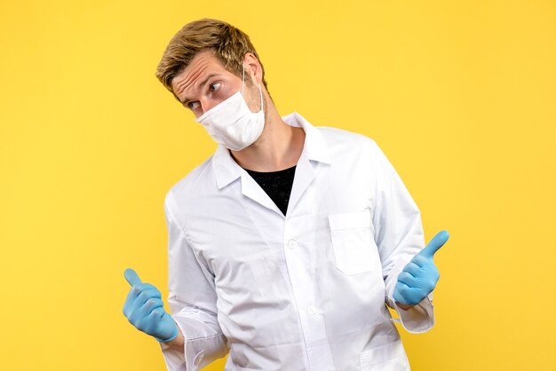 Vista frontal médico masculino sobre fondo amarillo virus de salud covid pandémico