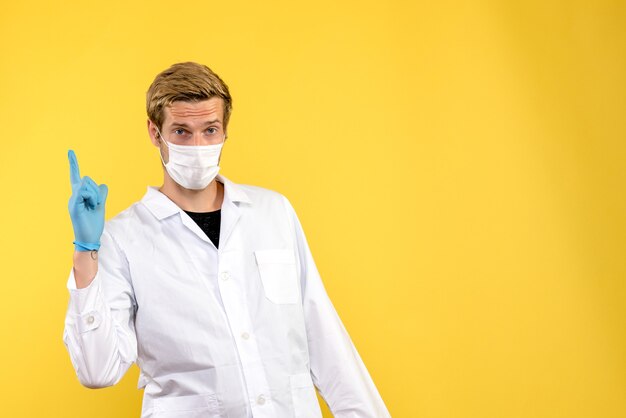 Vista frontal médico masculino sobre fondo amarillo virus de salud covid pandémico