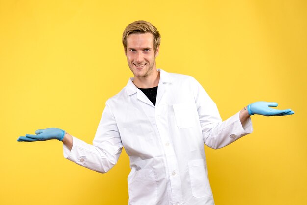 Vista frontal médico masculino sonriendo sobre fondo amarillo médico pandemia covid humano