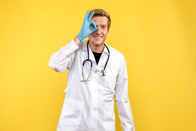 Vista frontal médico masculino sonriendo sobre fondo amarillo médico de virus humanos de salud