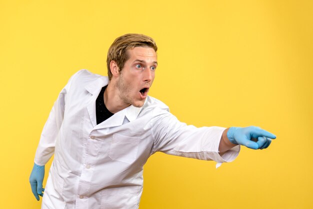 Vista frontal médico masculino sorprendido sobre fondo amarillo medic covid- hospital humano