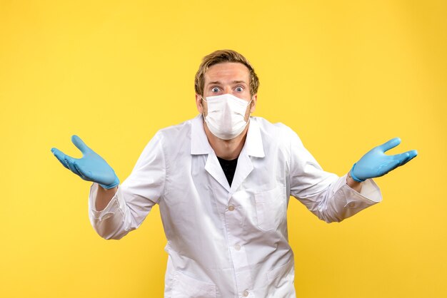 Vista frontal médico masculino sorprendido sobre fondo amarillo médico de salud covid pandémica
