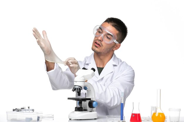 Vista frontal médico masculino en traje médico blanco con guantes en el espacio en blanco