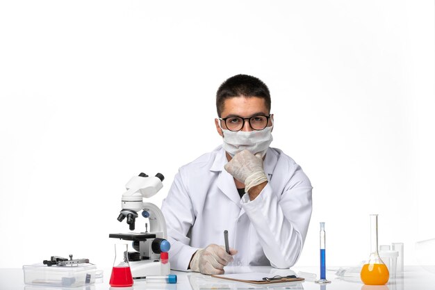 Foto gratuita vista frontal médico masculino en traje médico blanco y con máscara pensando en el espacio en blanco