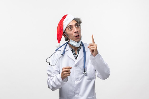 Vista frontal médico masculino en traje médico en la pared blanca año nuevo pandémico del virus covid