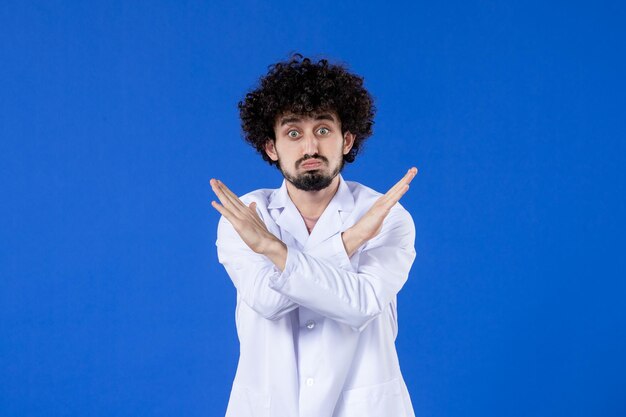 Vista frontal del médico masculino en traje médico sobre fondo azul medicina hospitalaria medicamento covid-virus pandemia salud vacuna