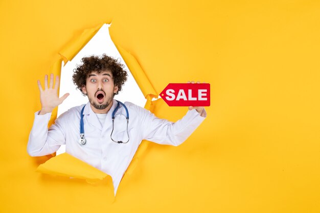 Vista frontal médico masculino en traje médico con venta roja escribiendo en amarillo médico color salud enfermedad virus compras hospital