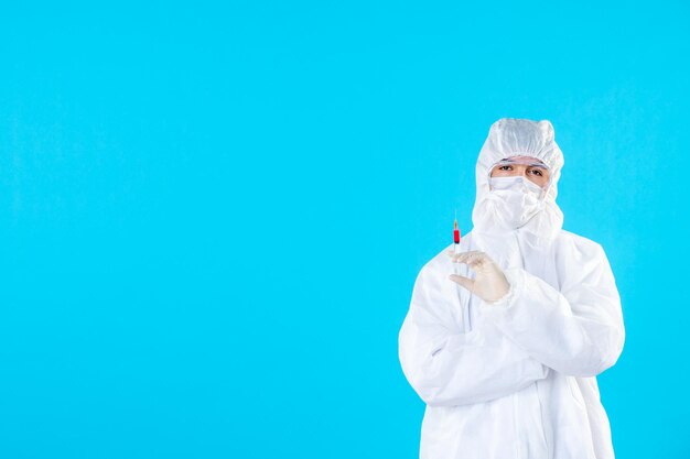 Vista frontal médico masculino en traje de protección con inyección en el azul