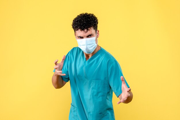 Vista frontal médico médico enojado en la máscara está hablando de sus pacientes