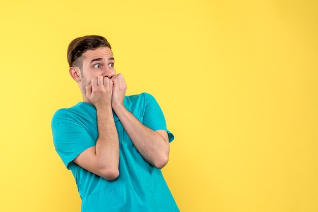 Vista frontal del médico de sexo masculino con cara muy asustada en la pared amarilla