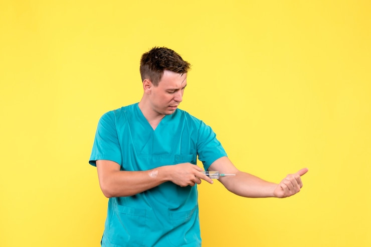 Foto gratuito vista frontal del médico de sexo masculino con inyección enorme en la pared amarilla