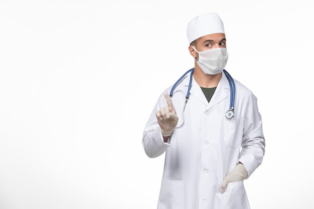 Vista frontal médico de sexo masculino con traje médico y máscara contra el coronavirus en el piso blanco, enfermedad del virus covid, enfermedad, aislamiento, pandemia