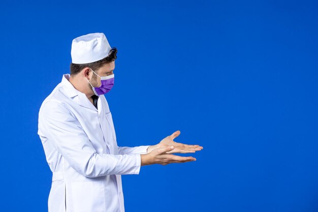 Vista frontal del médico de sexo masculino en traje médico y máscara púrpura sobre azul