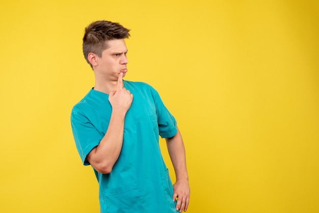 Vista frontal del médico de sexo masculino en traje médico en la pared amarilla