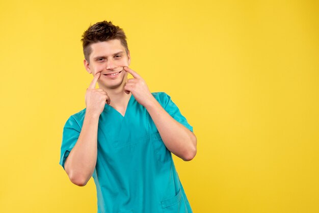 Vista frontal del médico de sexo masculino en traje médico en la pared amarilla
