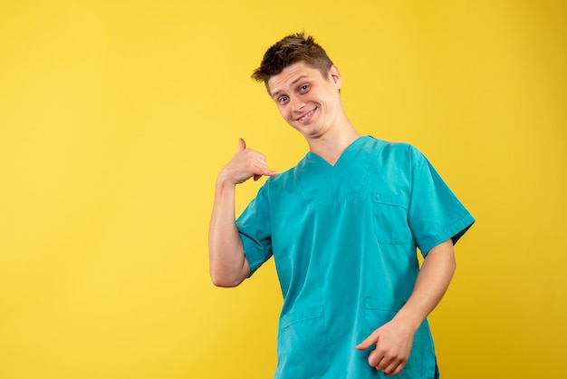 Vista frontal del médico de sexo masculino en traje médico en la pared amarilla