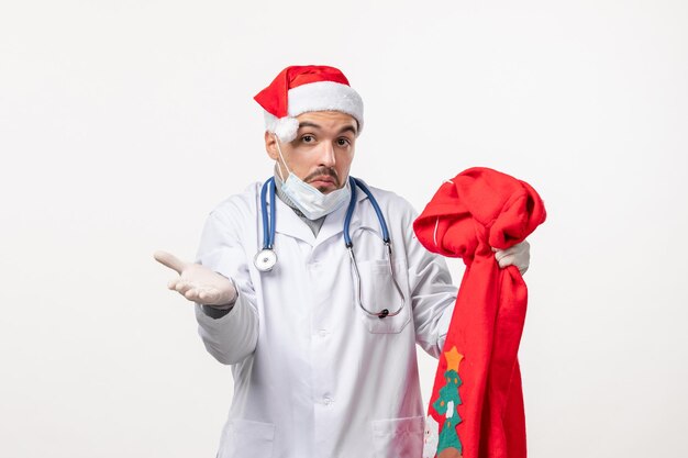 Vista frontal del médico varón con bolsa roja presente en la pared blanca