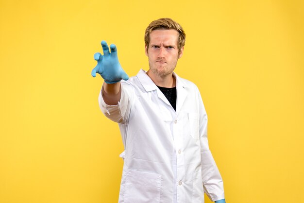 Vista frontal médico varón con cara enfadada sobre fondo amarillo médico de salud covid- pandemia