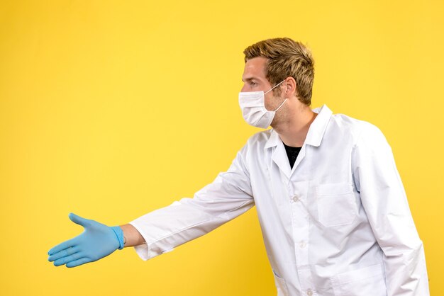 Vista frontal médico varón estrecharme la mano sobre fondo amarillo pandemia de virus covid de salud