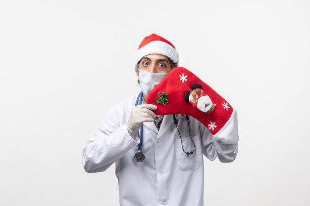 Vista frontal médico varón con gran calcetín rojo sobre piso blanco virus covid- navidad