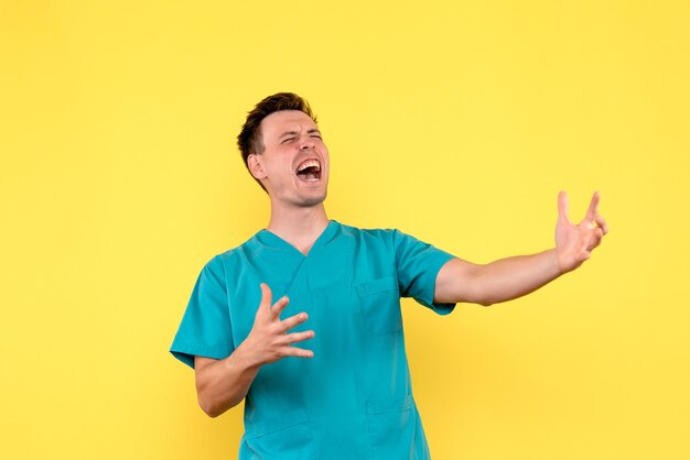 Vista frontal del médico varón gritando en la pared amarilla