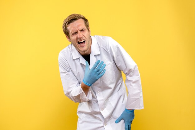 Vista frontal médico varón se lastimó la mano sobre fondo amarillo medic salud covid pandemia