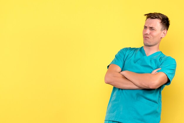 Vista frontal del médico varón mirando algo en la pared amarilla