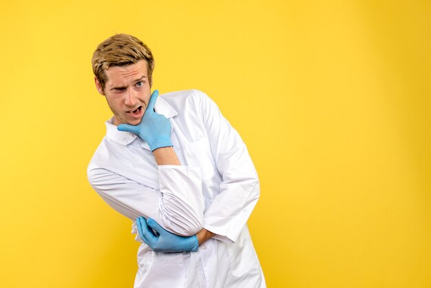 Vista frontal médico varón posando sobre fondo amarillo covid- médico del hospital humano