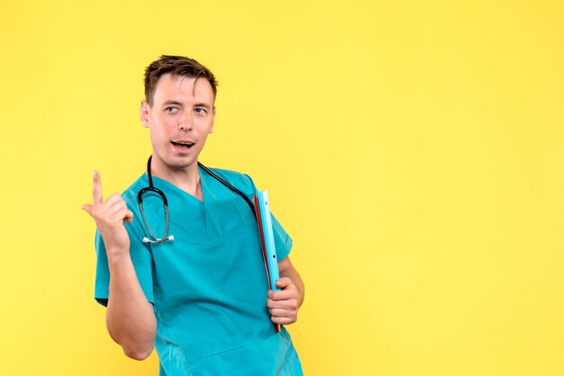 Vista frontal del médico varón sosteniendo análisis sobre piso amarillo médico médico del hospital