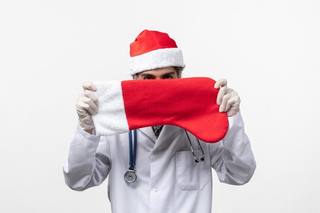 Vista frontal médico varón sosteniendo gran calcetín de vacaciones en la pared blanca virus covid holiday
