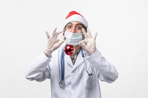 Vista frontal médico varón sosteniendo el virus covid de salud de juguete de árbol de año nuevo
