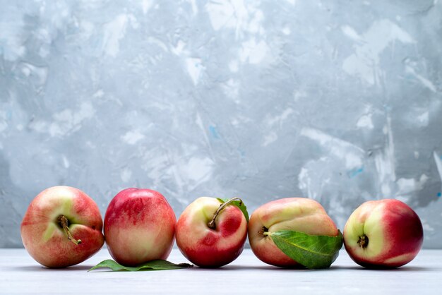 Una vista frontal melocotones frescos agrios y suaves sobre el fondo blanco color de la fruta fresca