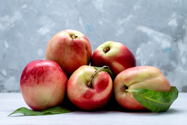 Una vista frontal de melocotones frescos agrios y suaves sobre el fondo blanco color de la fruta suave