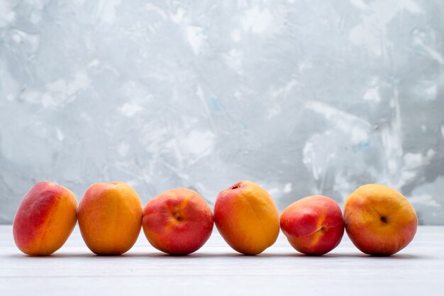 Una vista frontal melocotones frescos y suaves sobre el fondo blanco color de la fruta verano jugoso fresco